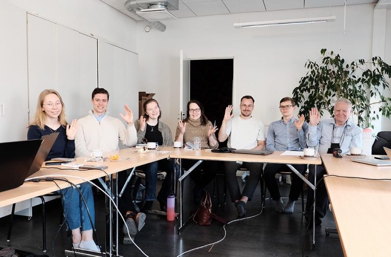 Pöydän ääressä vilkuttaa osa liittokokouksen osallistujista.